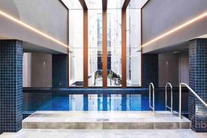 坎培拉的住宿－Midnight Luxe 1BR Executive Apartment in the heart of Braddon Views L7 Pool Sauna Gym Secure Parking Wifi Wine，一座带大窗户的建筑中的游泳池