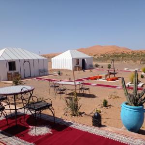 a group of tents with tables and chairs in the desert at Merzouga dreams Camp in Erfoud