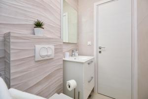 Baño blanco con lavabo y espejo en Green Lantern apartments Okuklje en Okuklje