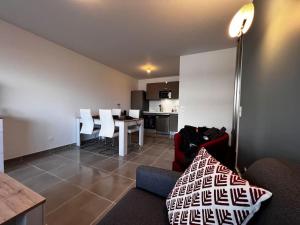 a living room with a couch and a table with chairs at T2 neuf + piscine, 5 mn à pied des plages in Sérignan