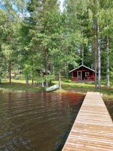 Un lago con un muelle de madera y una cabaña. en Koivurannan lomamökit Pihlaja, en Nykälä