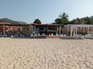 una playa de arena con sillas blancas y un restaurante en Casa Antonella, a pochi passi dalla spiaggia con stradello privato, en Solanas