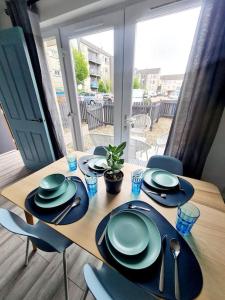 Una mesa de madera con platos y utensilios sobre ella. en Spacious 5bed house, FREE parking, NO PARTY !, en Glasgow