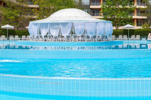 uma piscina com uma tenda, cadeiras e água em iHotel Sunny Beach em Sunny Beach