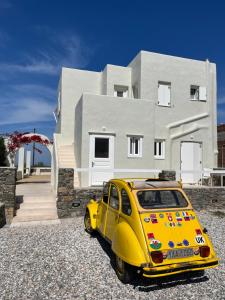 une voiture jaune garée devant une maison dans l'établissement The Black Pig Studios, à Posidhonía