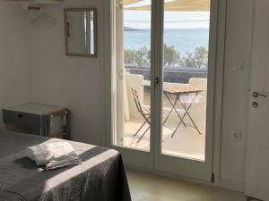 a bedroom with a bed and a balcony with a table at The Black Pig Studios in Posidhonía