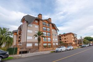 a building on the side of a street with parked cars at Apto 4 dormitórios em Canela - @stayhousetemporada in Canela