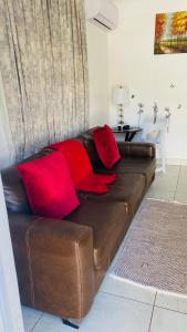 un sofá de cuero marrón con almohadas rojas en la sala de estar. en La Lucia Sleepover, en Durban