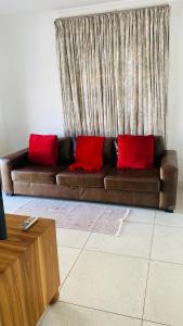 a brown couch with red pillows in a living room at La Lucia Sleepover in Durban