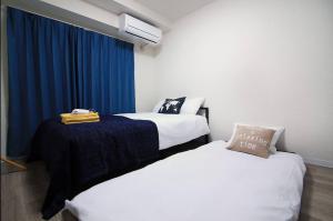 a room with two beds and a blue curtain at SG LION HOUSE 2P Free pocket Wi-fi! in Tokyo
