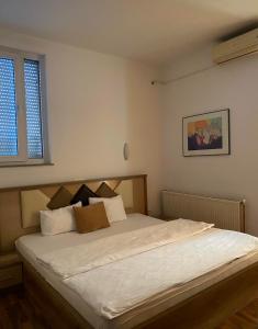 una camera da letto con letto, lenzuola e cuscini bianchi di Golden BnB Hotel a Pristina