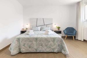 a bedroom with a large bed and a blue chair at Apartamentos El Mirador in Villarroya de los Pinares