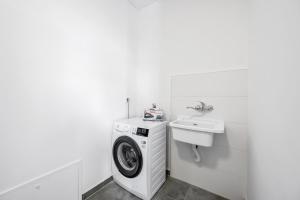 una lavanderia bianca con lavatrice e lavandino di theTinel a Zaboric