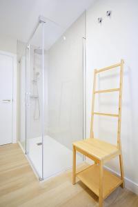 um chuveiro com uma porta de vidro e uma cadeira de madeira em Apartamento Aires de Lavanda em Sanxenxo
