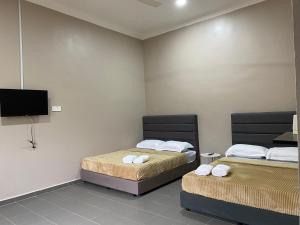 a room with two beds and a flat screen tv at Sasuka Guesthouse (Muslim Sahaja) in Marang