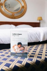 een boek op een bed met een spiegel bij Hotel De Kroon Gennep in Gennep