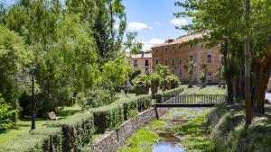 a bridge over a river in a park with a building at Apartamentos El Mirador in Villarroya de los Pinares