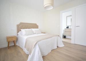 um quarto branco com uma cama grande e lençóis brancos em Apartamento Aires de Lavanda em Sanxenxo