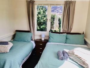 two beds in a room with a window at Northern Holiday Cottage in Whangarei