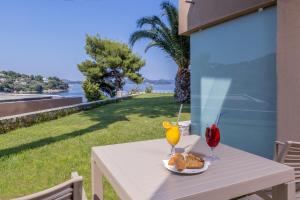 a table with a plate of bread and two glasses of juice at Cape Kanapitsa Hotel & Suites in Kanapitsa