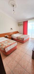 two beds in a room with a tiled floor at Gazipasa Star Otel in Side