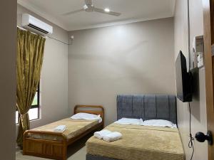 a room with two beds and a television in it at Sasuka Guesthouse (Muslim Sahaja) in Marang
