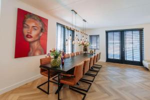 een eetkamer met een groot schilderij van een vrouw bij Brand new bright & luxurious villa in Amsterdam! in Amsterdam