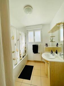 Baño blanco con lavabo y espejo en Maison entière Domido, en Changé