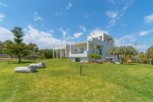 a large white house on a grassy field at Legrena Beach House in Sounio