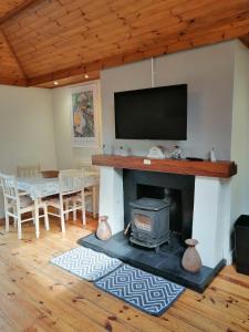 uma sala de estar com lareira e televisão de ecrã plano em An Cúinín em New Ross