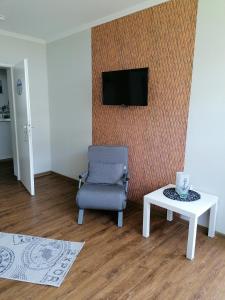 a living room with a chair and a tv on a wall at Ferienwohnung Breitschuhs Havenwelten Bremerhaven in Bremerhaven