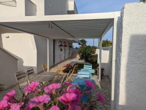 un patio con mesas, sillas y flores rosas en b&b Bellavista, en Castro di Lecce