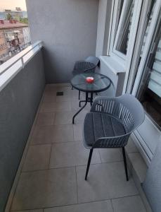 balkon z 2 krzesłami, stołem i oknem w obiekcie Banja Luka apartment w mieście Banja Luka