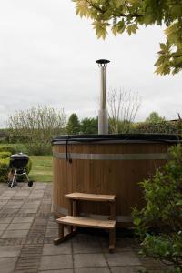 a wooden hot tub with a bench and a grill at Villa Rust-en-Vrede met hottub in Zeewolde
