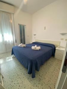 1 dormitorio con 1 cama azul y 2 toallas en B&B Hotel Lucciola en Cattolica