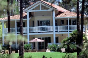 Una gran casa blanca con un porche envolvente en Lagrange Vacances - Eden Parc Golf, en Lacanau-Océan