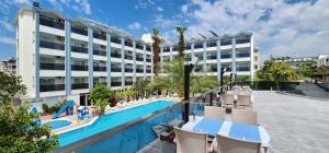a hotel with a swimming pool with chairs and a building at Gazipasa Star Otel in Side