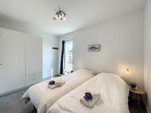 a bedroom with a bed with white sheets and a window at Villa SeaShell - Luxurious renovated gas station in Koksijde