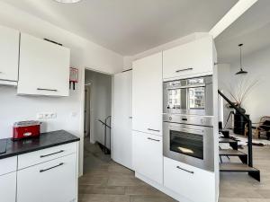 una cucina con mobili bianchi e un forno di Villa SeaShell - Luxurious renovated gas station a Koksijde