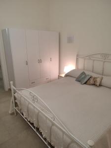 - une chambre avec un lit blanc et une armoire blanche dans l'établissement Le Casette di Adele, à Palagiano