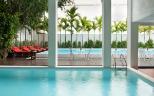 a swimming pool with chairs and a table in a building at Mane Colonial Classic in Siem Reap