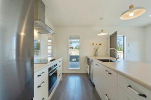 a large kitchen with white cabinets and a sink at Cosy and Central in Taupo