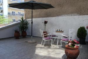 un patio con mesa, sillas y sombrilla en CasaTu 2 Apartments, en Komotiní