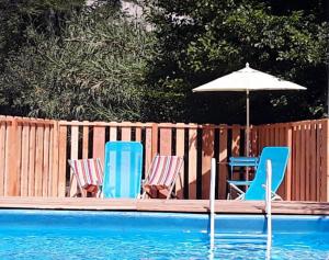 two chairs and an umbrella next to a swimming pool at Bungalow de 2 chambres avec piscine partagee jardin clos et wifi a Saint Jean de Valeriscle in Saint-Jean-de-Valériscle