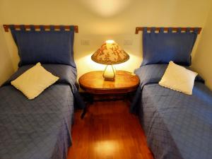 Appartamento Teresina في مارشانا مارينا: غرفة نوم بسريرين وطاولة بها مصباح