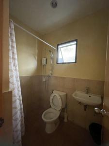 a bathroom with a toilet and a sink and a window at Astra Bella Apartment - Unit 2 in Dumaguete