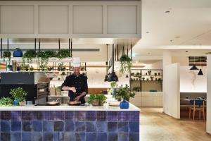 a man standing in a kitchen with a counter at Falkensteiner Family Hotel Diadora in Zadar