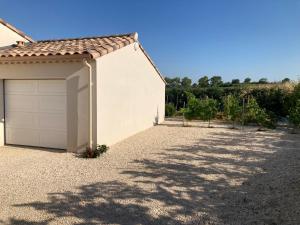 un garage blanc avec toit dans une allée dans l'établissement La maison aux palmiers, à Arpaillargues-et-Aureillac