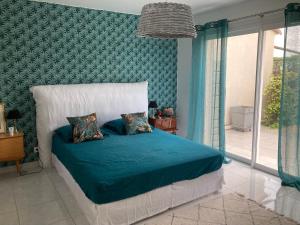 - une chambre avec un lit et une couette bleue dans l'établissement La maison aux palmiers, à Arpaillargues-et-Aureillac