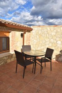 una mesa y sillas en un patio con una pared de piedra en Casa Rural del Pantano 4 Estrellas, 